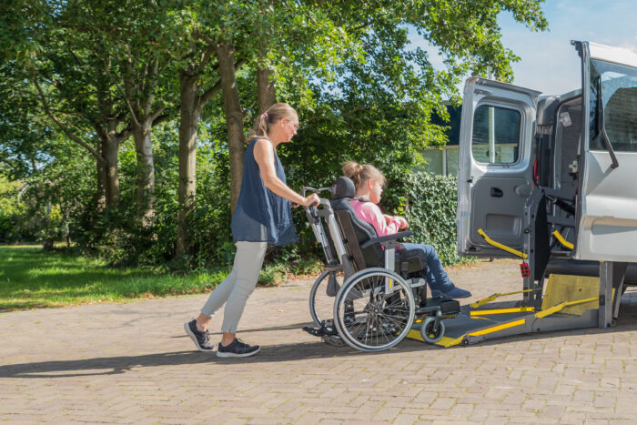 A disabled child in a wheelchair being cared for by a voluntary care worker.