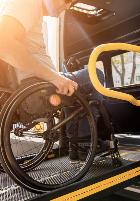 A man in a wheelchair on a lift of a vehicle for people with disabilities.